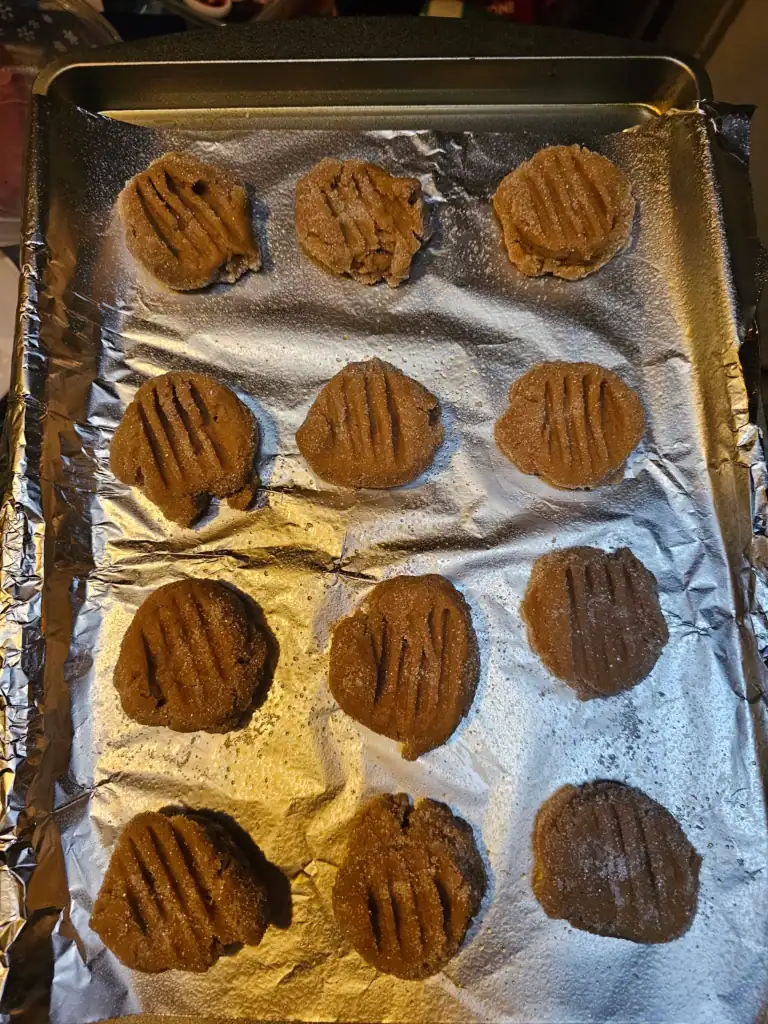 Super soft peanut butter cookies on baking sheet before being baked rolled in sugar and crossed on top with a fork