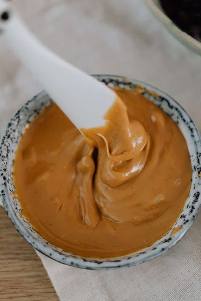 Silky peanut butter frostingbeing stirred, perfect for desserts, with a close-up of its creamy texture and rich, golden-brown color. Ideal for sweet treats and baking.