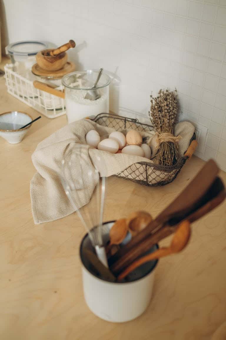 A cozy still life in a kitchen with eggs, flour, and utensils arranged stylishly.