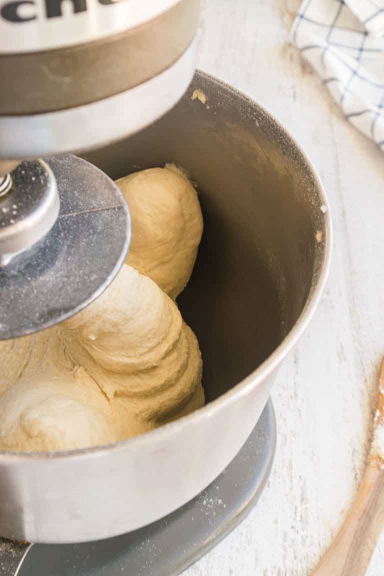A high angle view of dough being mixed in a stand mixer bowl, ideal for baking projects.