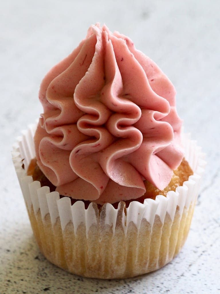 A pink frosted cupcake, perfect for dessert lovers, showcasing rich creamy swirls.